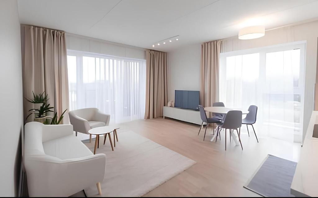 a living room with white furniture and a table and chairs at 7th floor Tallinn in Iru