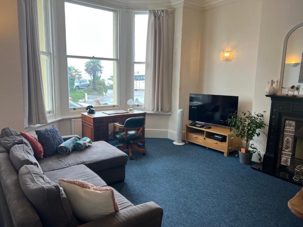 a living room with a couch and a desk and a television at One Queens Gardens, Sea View Apartment, Eastbourne. in Eastbourne