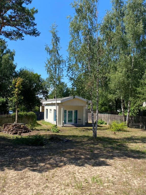 una pequeña casa blanca en un patio con árboles en Holiday HOUSE Vecāķi, en Riga