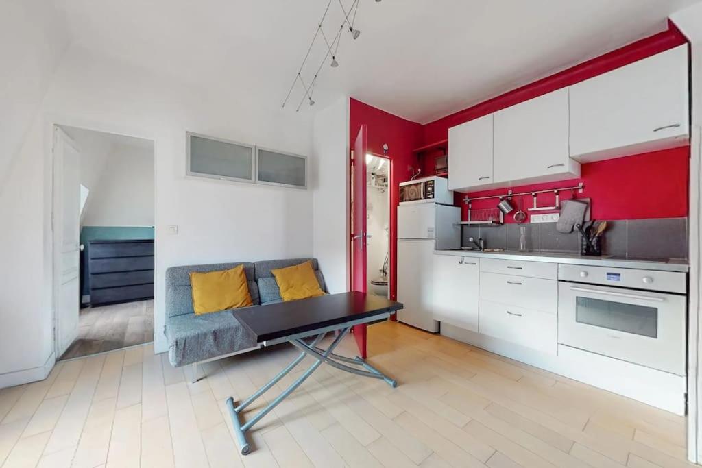 een keuken met rode en witte muren en een tafel bij 2 pièces Lumineux & Calme (28m²) in Parijs
