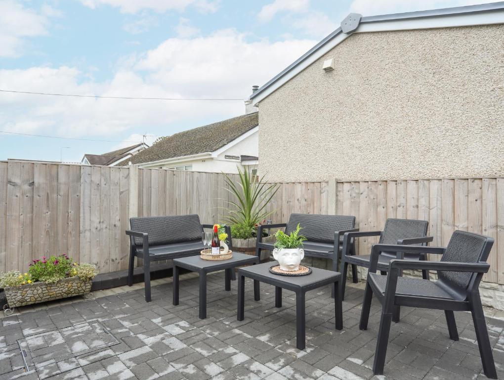 a patio with chairs and tables and a fence at Rhiwlas Bach in Benllech