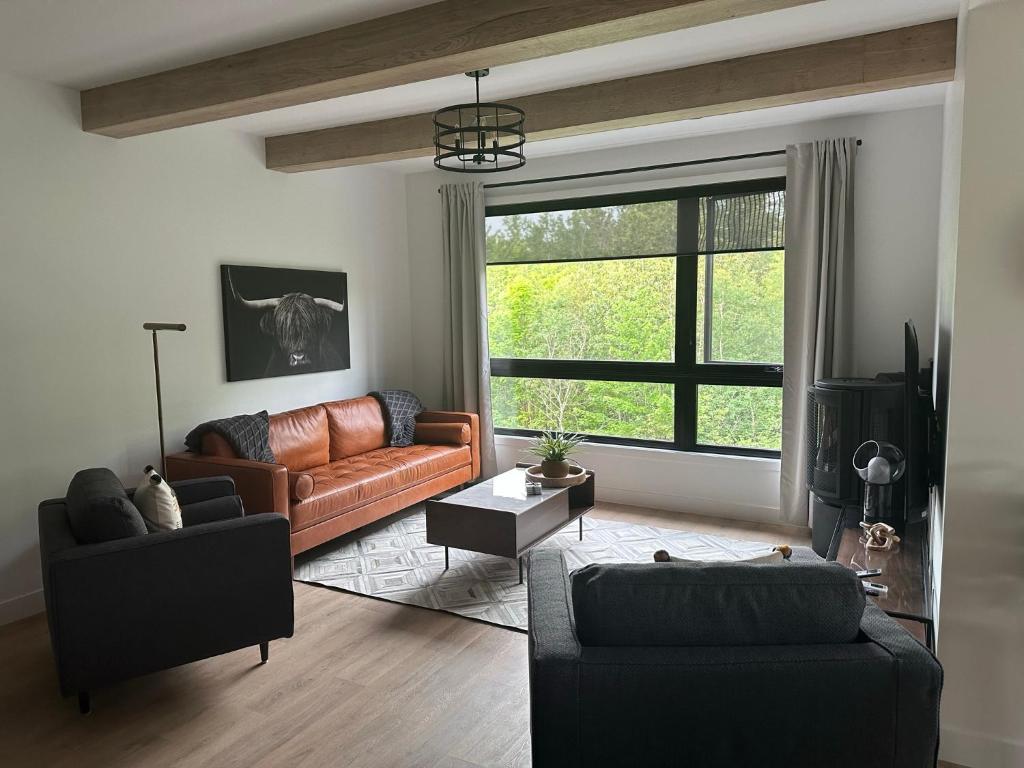 ein Wohnzimmer mit einem Ledersofa und einem Fenster in der Unterkunft Le Joford in Orford