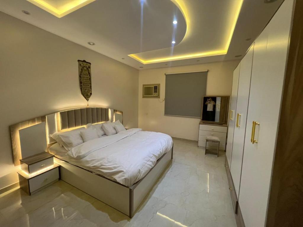 a bedroom with a white bed and a chalk board at شقة كبيرة 3 غرف نوم وصالة Large apartment with 3 bedrooms and a living room in Taif