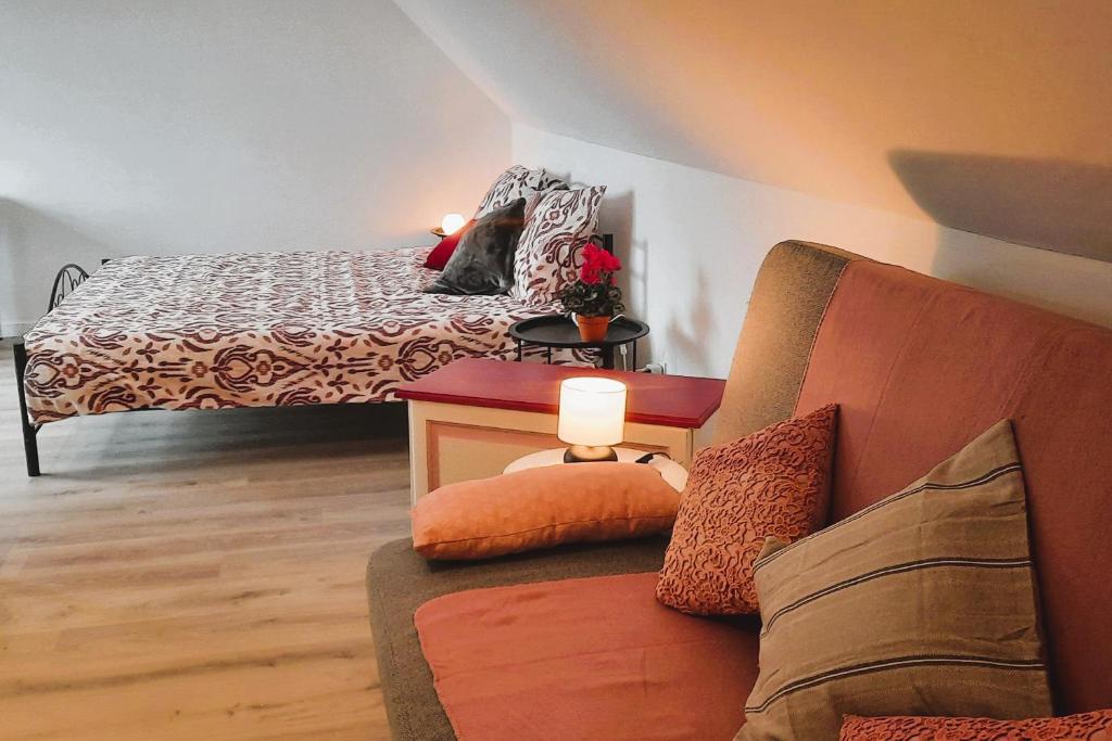 a bedroom with a bed and a couch with a lamp at BnB Waterzicht in Wijnegem
