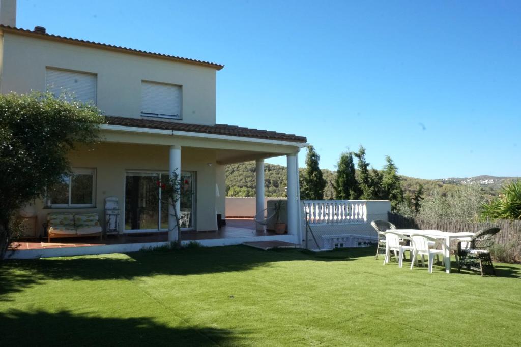 a house with a lawn with tables and chairs at Habitación Atalaya in Olivella