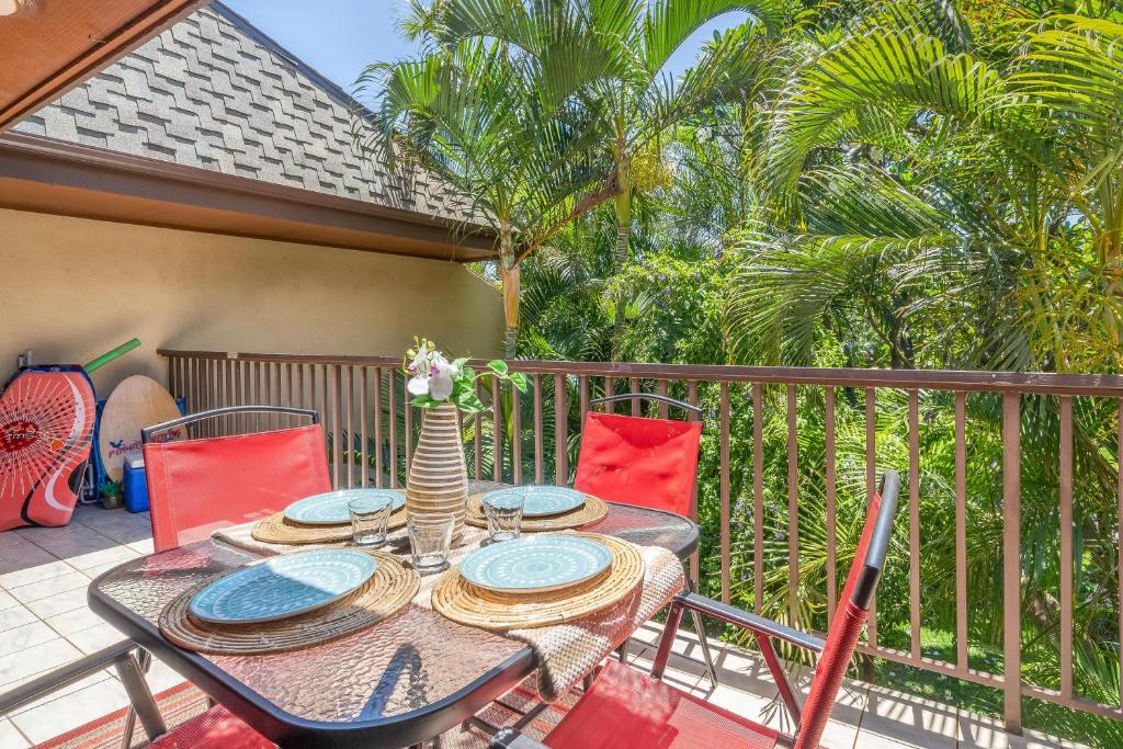 uma mesa e cadeiras numa varanda com palmeiras em Koa Resort 3J em Kihei