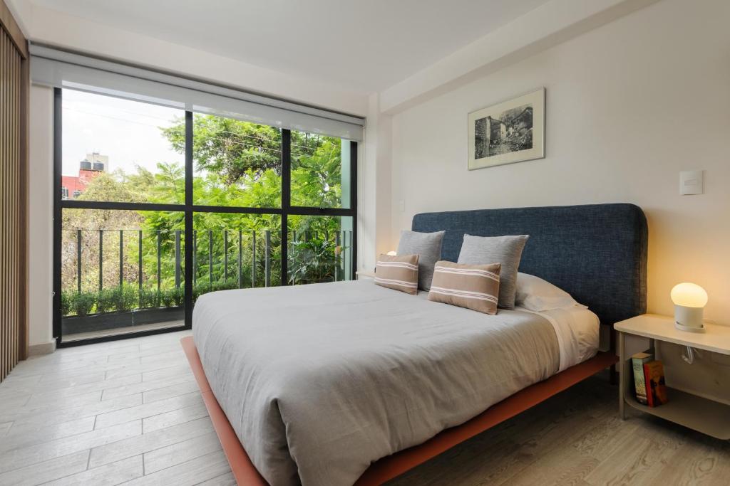 a bedroom with a large bed and a large window at Choapan 28 - Lux Apartments in Condesa in Mexico City
