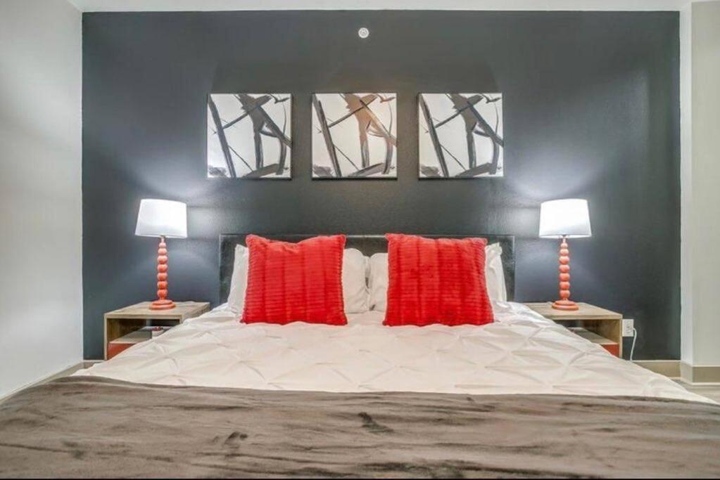 a bedroom with a large bed with two red pillows at Downtown Dallas 2bd free parking in Dallas