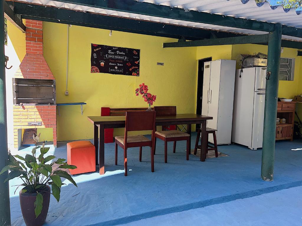 a patio with a table and chairs and a refrigerator at Hostel Coraticum in Ubatuba