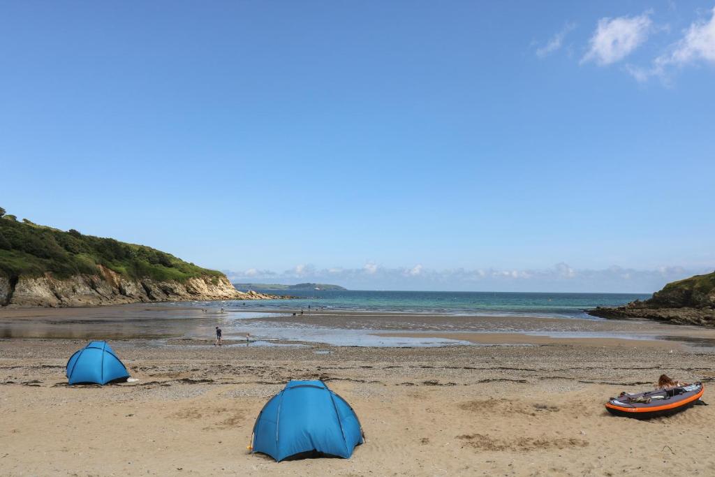 two tents on a sandy beach next to the ocean at Pugwash Cottage in Falmouth