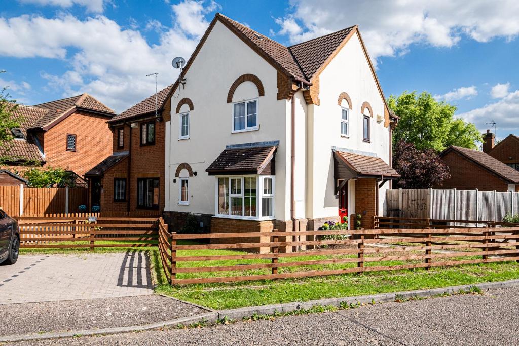 een wit huis met een houten hek bij Wheatley House in Milton Keynes