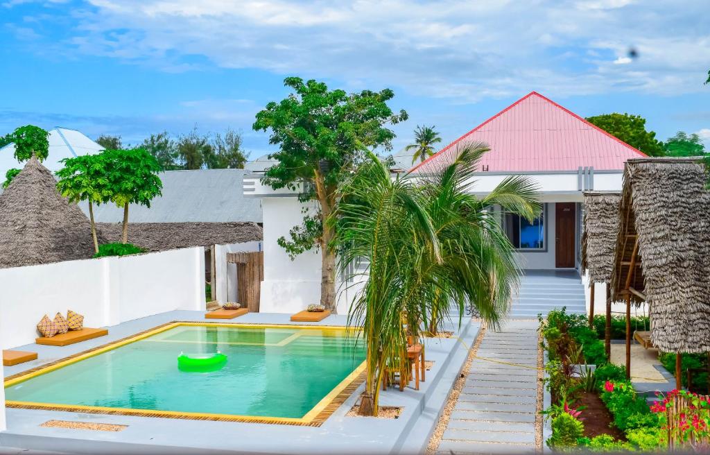 a villa with a swimming pool in front of a house at Uhuru House And Restaurant in Nungwi
