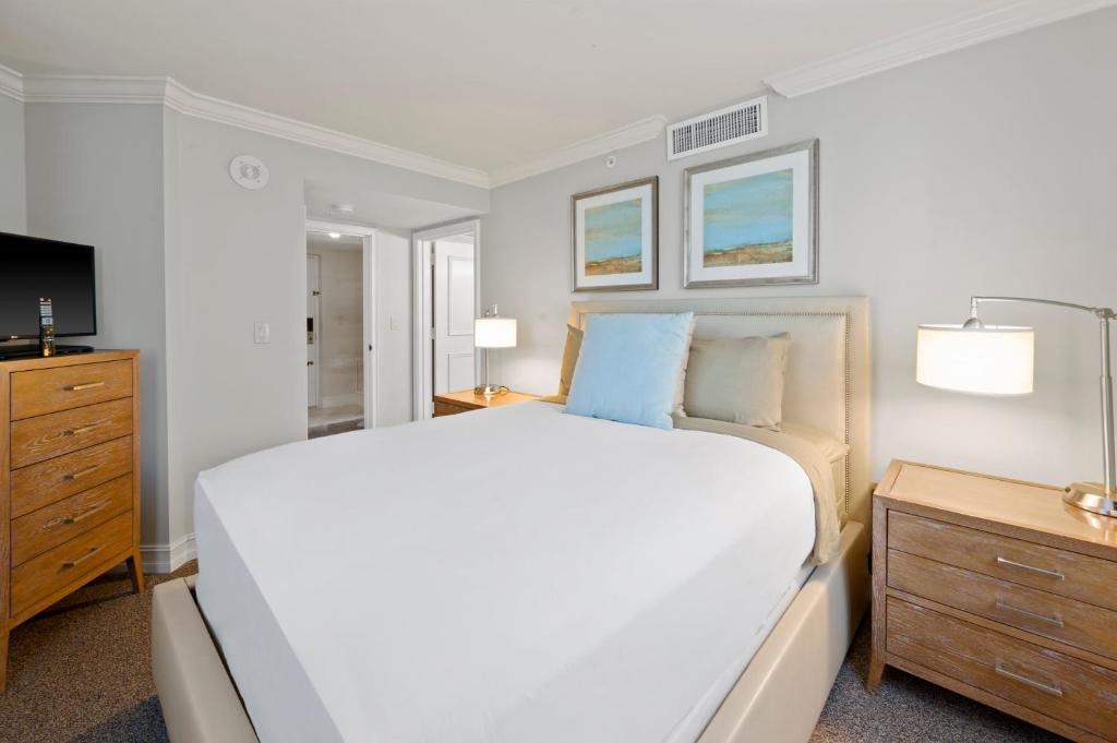 a white bedroom with a large bed and a television at Marco Beach Ocean Suites in Marco Island