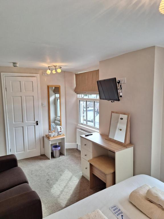 Cette chambre comprend un lit et un bureau avec une télévision. dans l'établissement Ferndale Lodge, à Ambleside