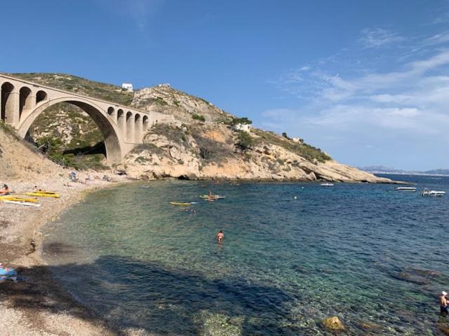 un pont sur une étendue d'eau à côté d'une plage dans l'établissement Joli appartement avec chambre et grande terrasse à deux pas de la mer, à Sausset-les-Pins