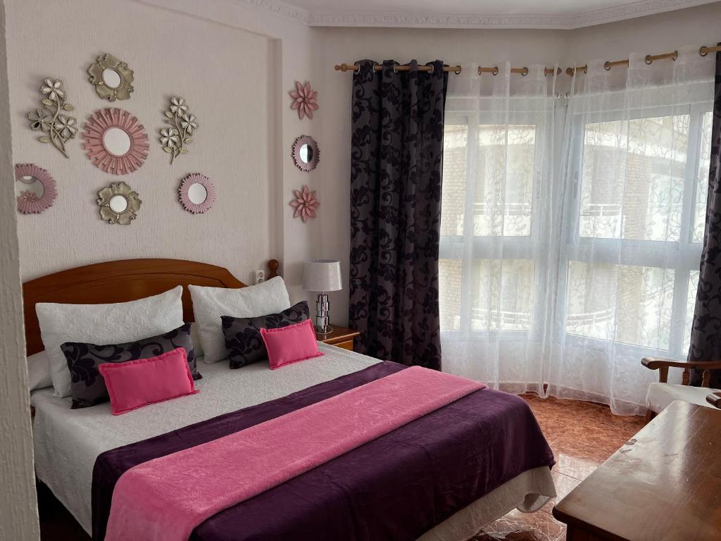 プエルト・デ・ラ・クルスにあるVista Rosmaryのベッドルーム1室(ピンクの枕が付いた大型ベッド1台付)