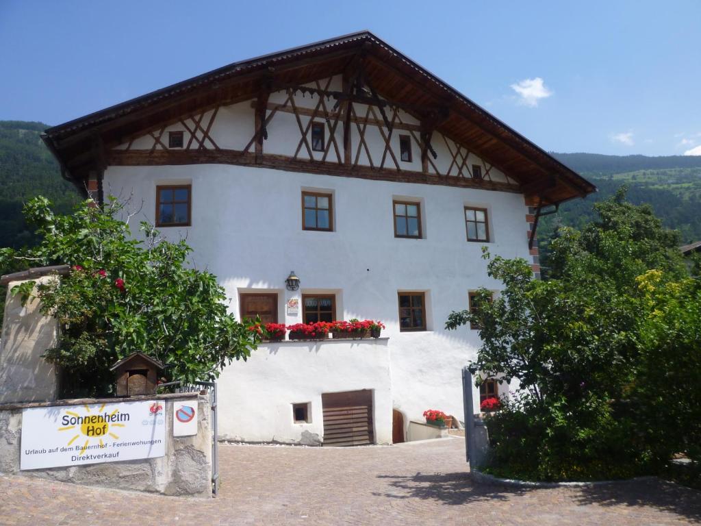 ein großes weißes Gebäude mit roten Blumen drauf in der Unterkunft Sonnenheimhof in Mals im Vinschgau