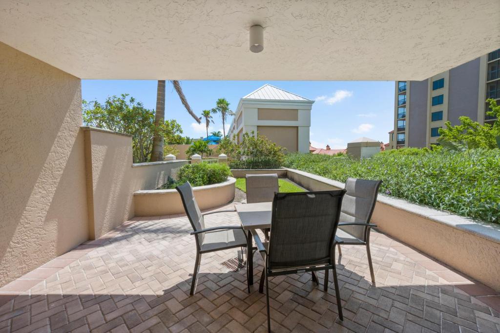 eine Terrasse mit Tisch und Stühlen und ein Gebäude in der Unterkunft Marco Beach Ocean Suites in Marco Island