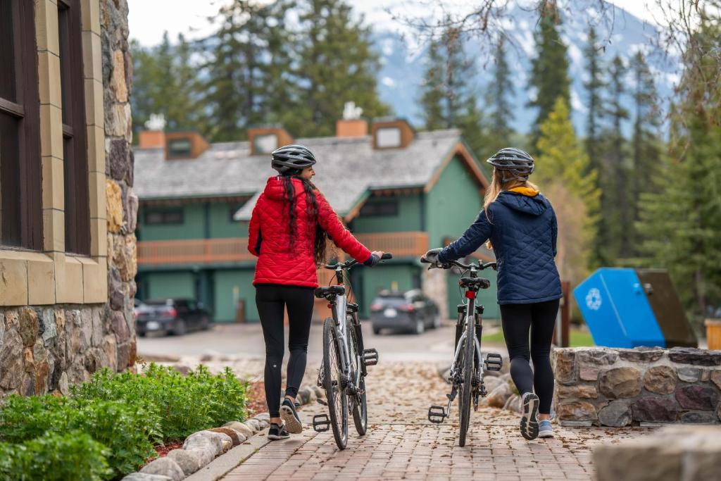 two women walking their bikes outside a building at Lake Louise Inn in Lake Louise
