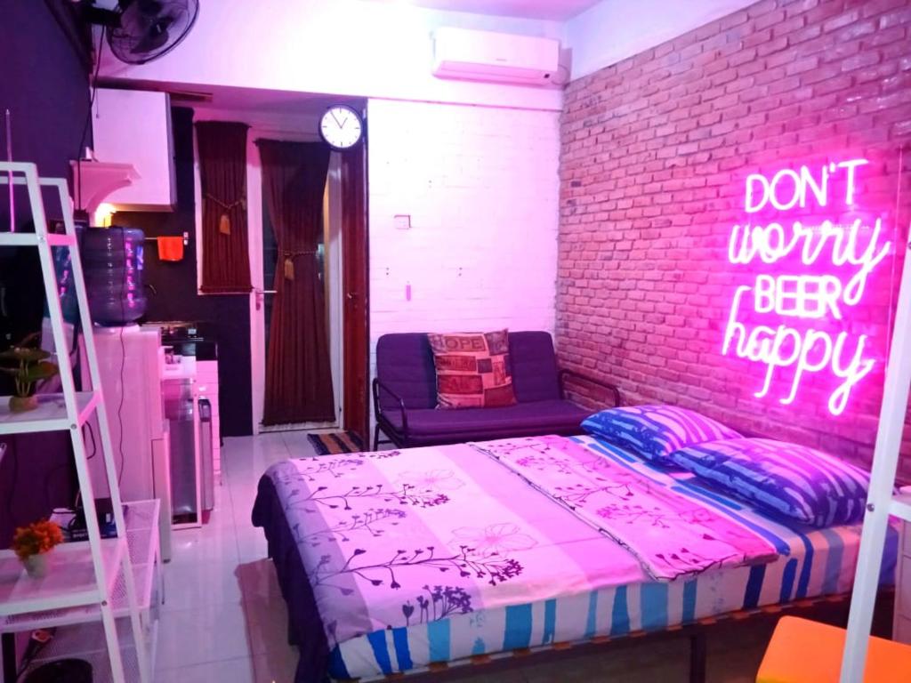 a bedroom with a bed and a brick wall with a neon sign at Apartemen Green Lake View Ciputat by My Rooms in Pondokcabe Hilir