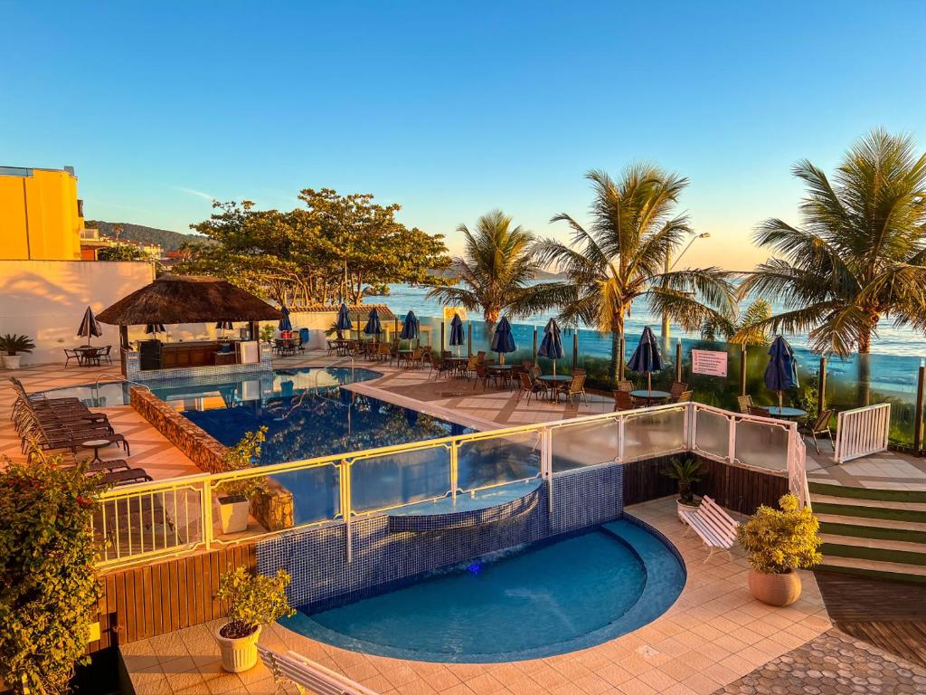 a resort pool with a view of the ocean at Pousada Vila do Coral in Bombinhas