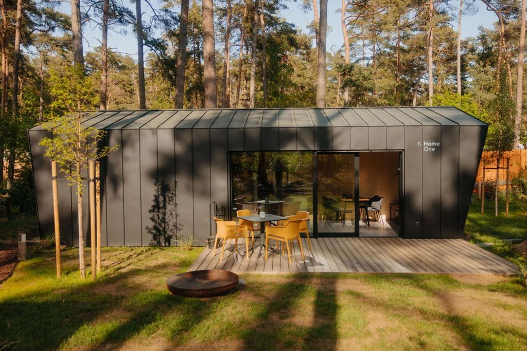 un cobertizo negro con una mesa y sillas en un patio en Cabin28 en Lubmin