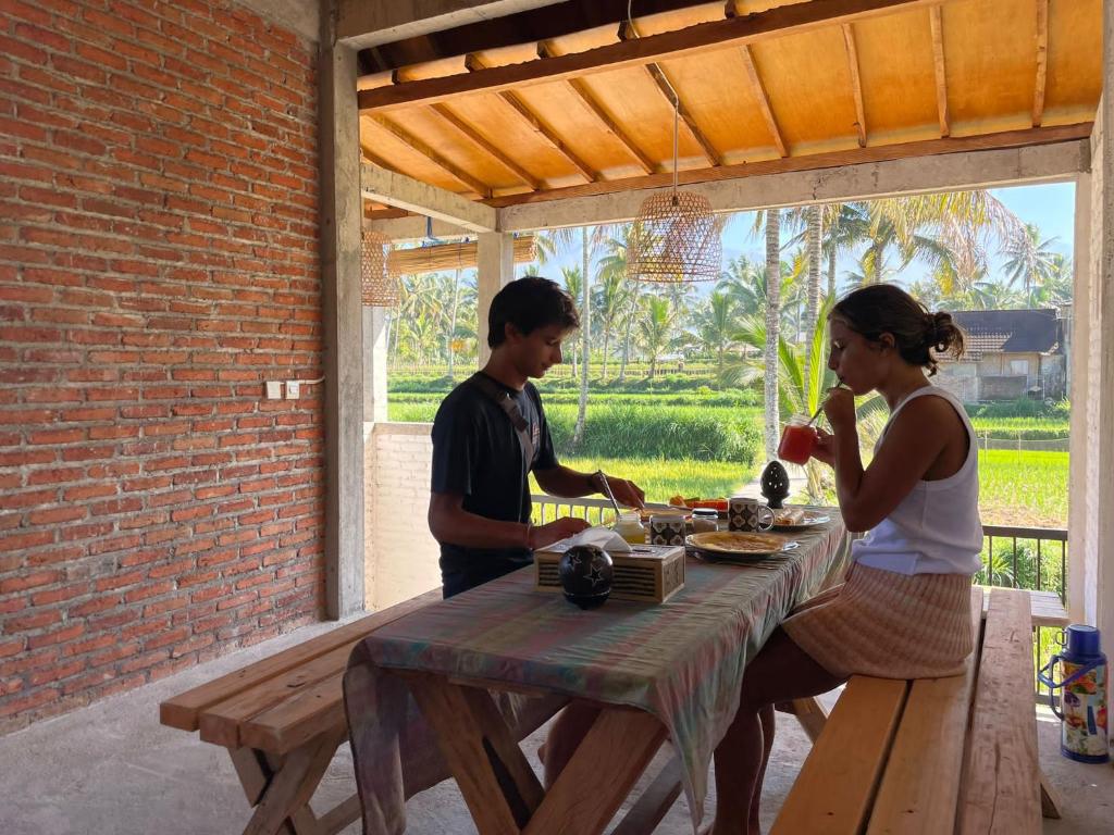 Un uomo e una donna seduti a un tavolo da picnic di MyHome - Lombok a Tetebatu