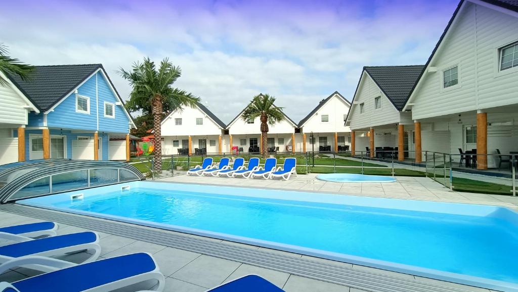 a swimming pool with blue chairs and some houses at Fe / Ha STAR- SUNNY RELAX in Bobolin