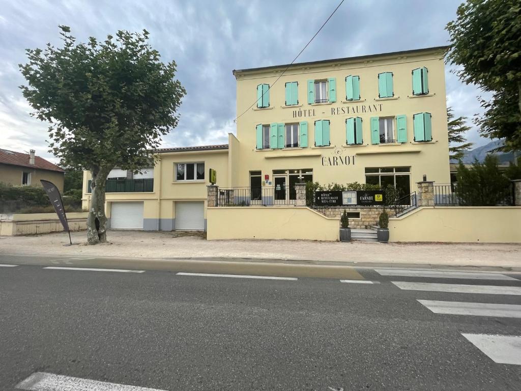 ディーにあるLOGIS HOTEL & RESTAURANT Le CARNOTの通路上の青窓のある黄色い建物