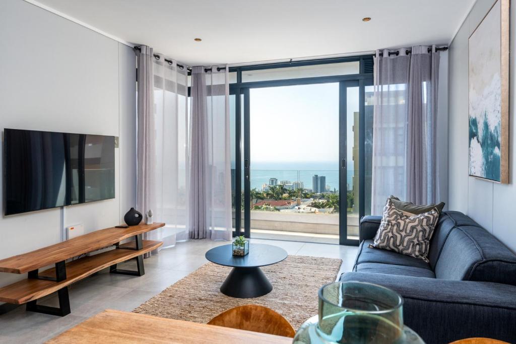 a living room with a blue couch and a large window at Luxury Bellagio 302 with Sea Views and Inverter in Durban
