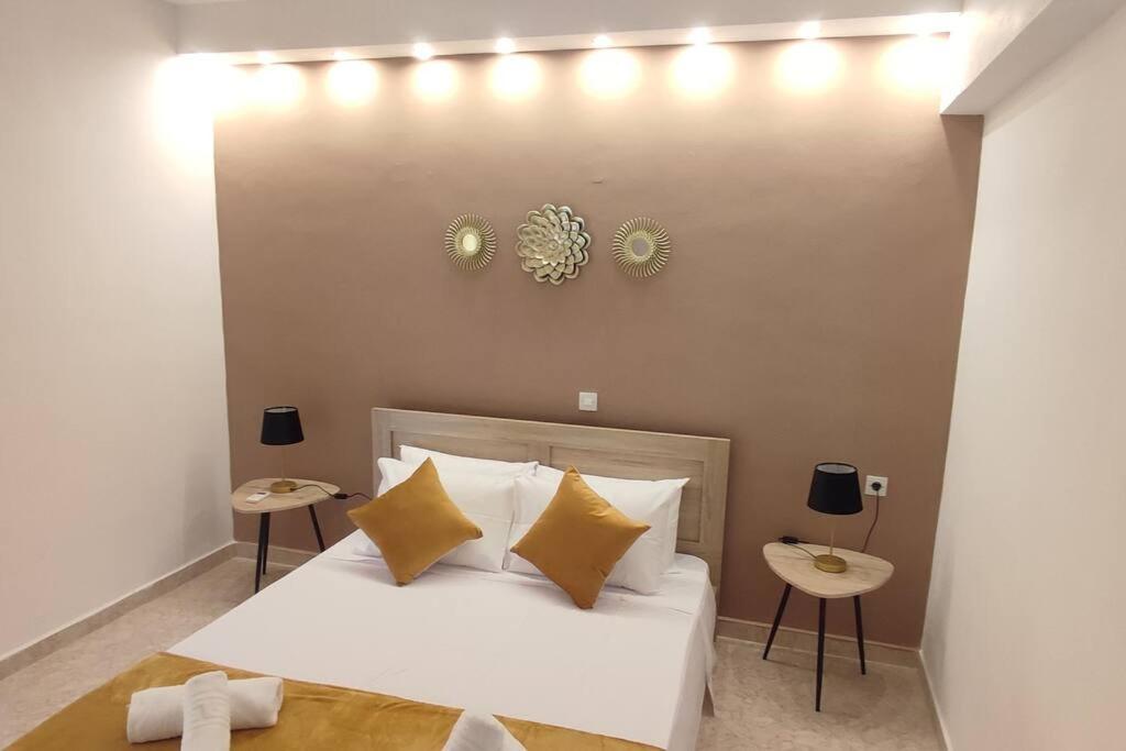 a bedroom with a bed with yellow pillows and two tables at Tilos Pearl in Livadia