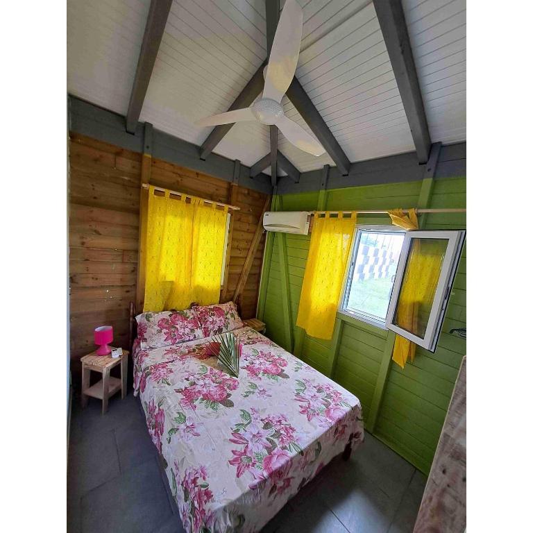 a bedroom with a bed and a ceiling fan at Les bungalows de Pipo 1 in Anse-Bertrand