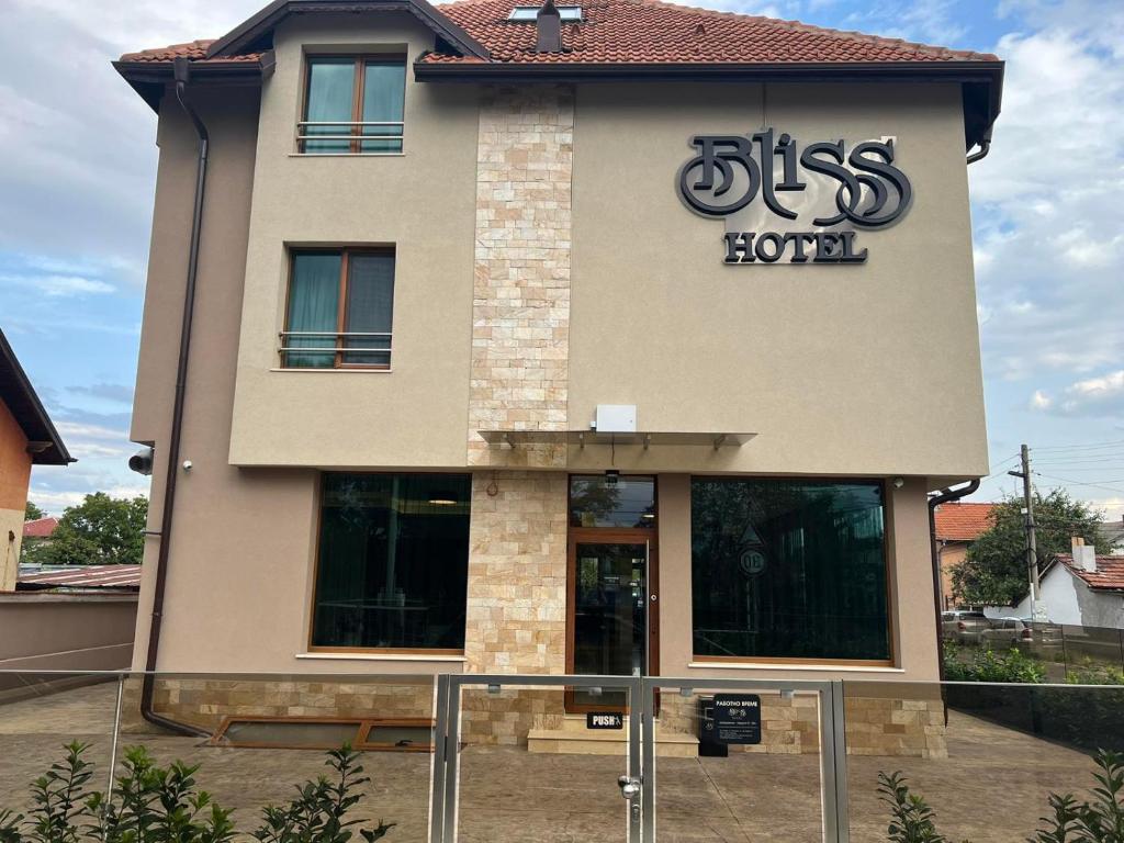 a building with a sign on the side of it at Хотел BLISS in Kazichene