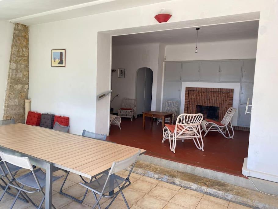 ein Wohnzimmer mit einem Tisch, Stühlen und einem Kamin in der Unterkunft Grande villa face à la plage, superbe vue mer in La Seyne-sur-Mer