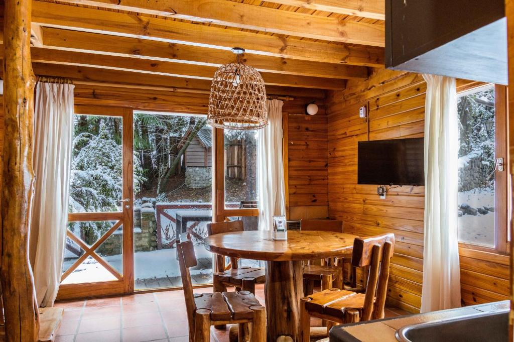 Un comedor con una mesa y un gran ventanal. en BOG Torres del Bayo, en Villa La Angostura