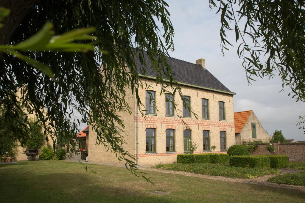 Holiday Home Slaghekhoeve في Nieuwkapelle: منزل من الطوب كبير مع سقف أسود
