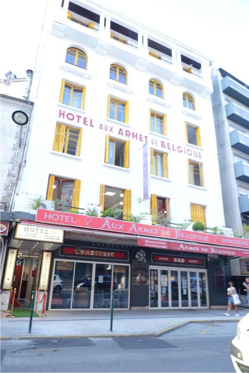 - un grand bâtiment blanc avec un panneau rouge dans l'établissement Hôtel Aux Armes de Belgique, à Lourdes
