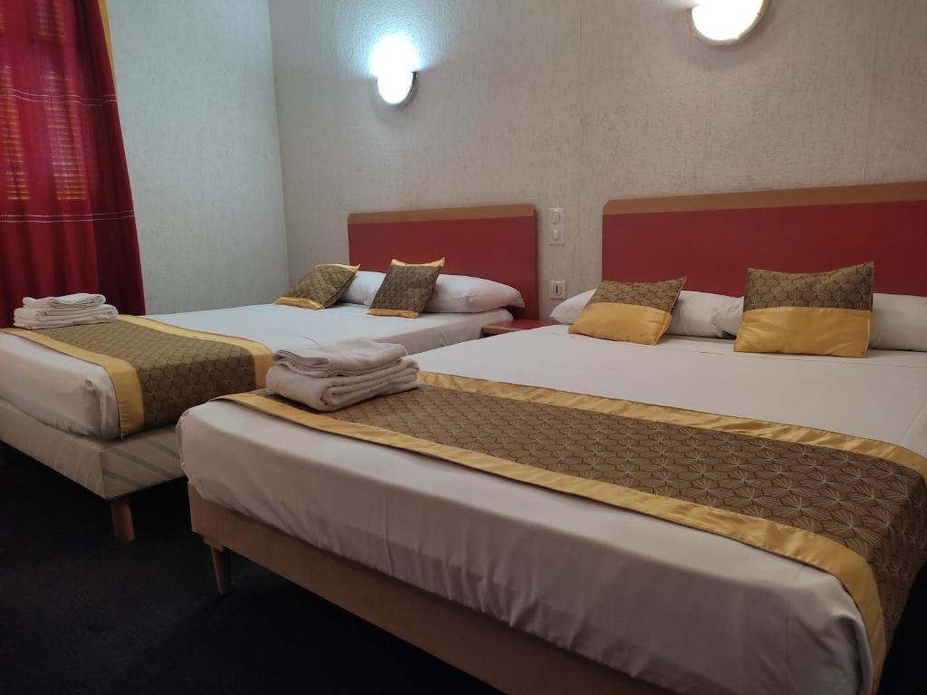 2 letti in camera d'albergo con asciugamani di Hôtel Aux Armes de Belgique a Lourdes