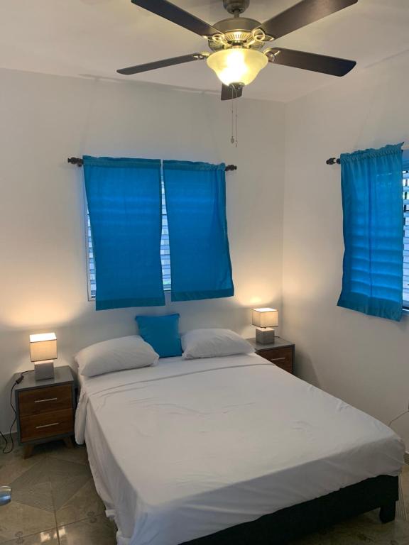 a bedroom with a bed with blue curtains and a ceiling fan at Caribbean Domicile in Las Terrenas
