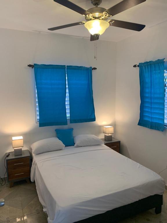 een slaapkamer met een bed met blauwe gordijnen en een plafondventilator bij Caribbean Domicile in Las Terrenas