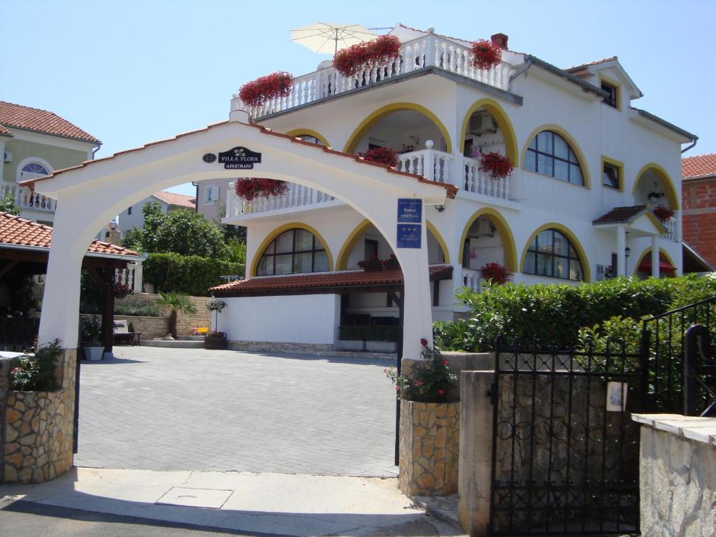 a white building with an arch in front of it at Villa Flora in Malinska