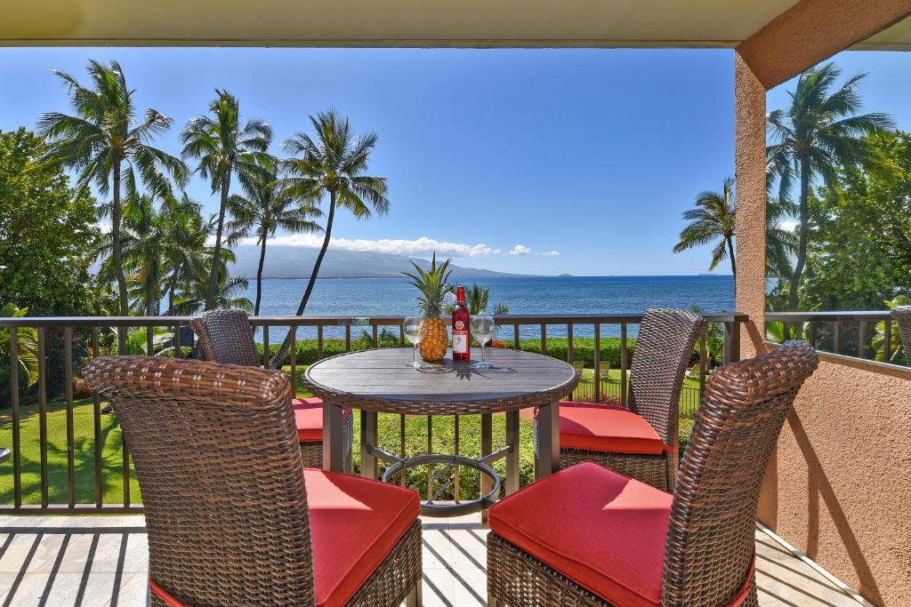 a table and chairs on a balcony with the ocean at Maalaea Banyans 203 in Wailuku
