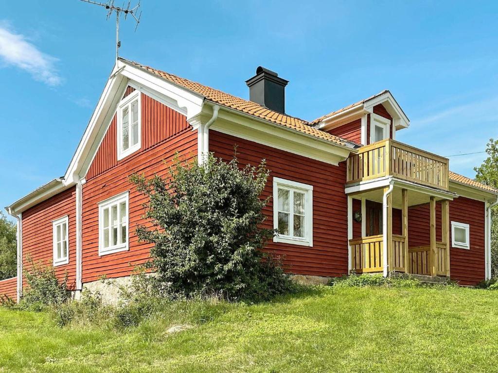 una casa roja con una terraza a un lado. en 8 person holiday home in VALDEMARSVIK, en Valdemarsvik