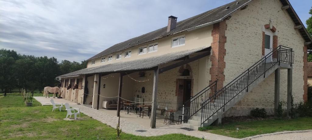 ein Gebäude mit Tischen und Stühlen und einem Pferd im Hintergrund in der Unterkunft Gîte groupe 6 à 12 pers. cœur de forêt d'Orléans - SPA Hammam Sport in Lorris