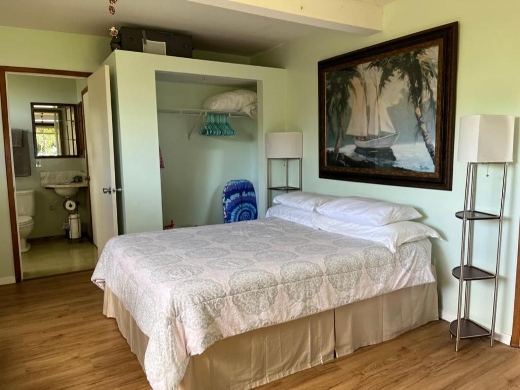 a bedroom with a bed and a painting on the wall at Waipio Studio Apartment in Kukuihaele