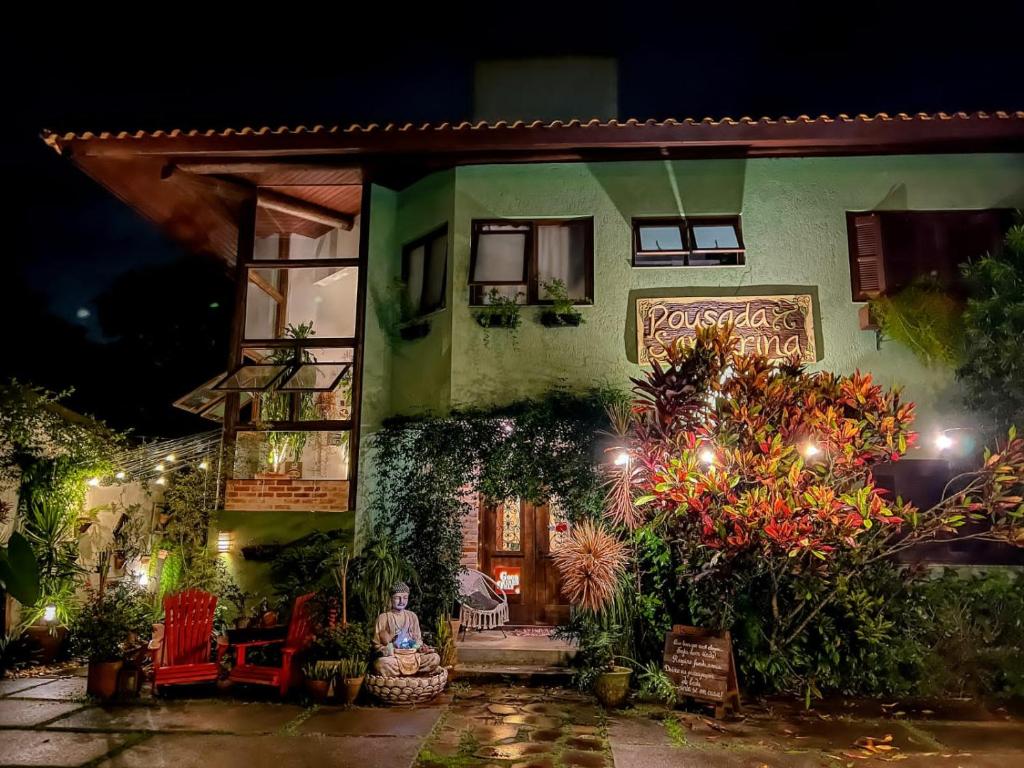 une maison avec une femme assise devant elle la nuit dans l'établissement Pousada Santarina, à Florianópolis