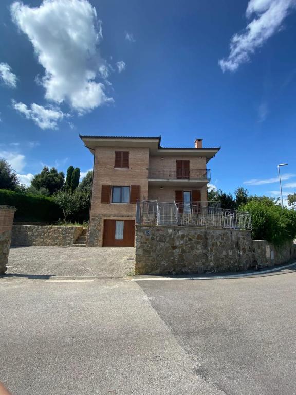 une maison avec un mur en pierre en face d'une rue dans l'établissement Casa Vacanze la Pineta, à Montalcino