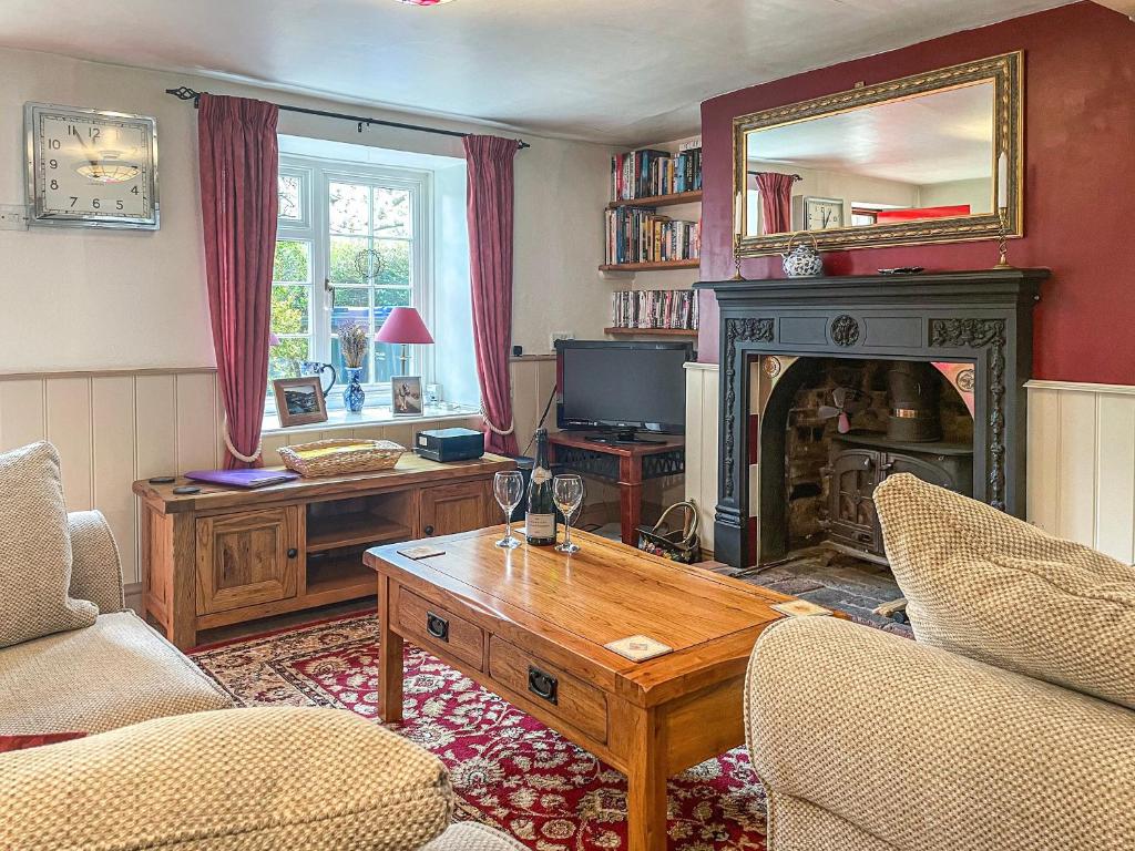 a living room with a fireplace and a table at Mays Cottage in Melbury Abbas