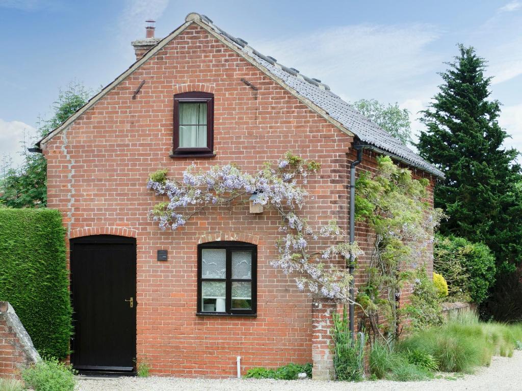 uma casa de tijolos vermelhos com uma porta preta em The Small Barn em Wood Norton