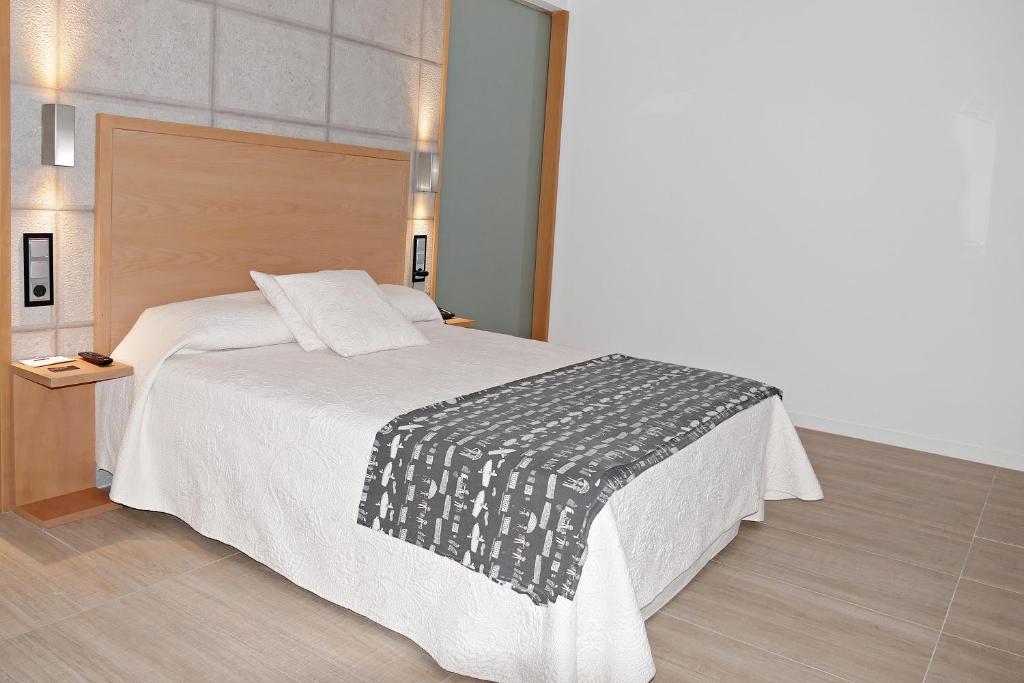 a hotel room with a bed, desk and a lamp at Hotel Rural Piedra Y Luz in Hinojosa del Duque
